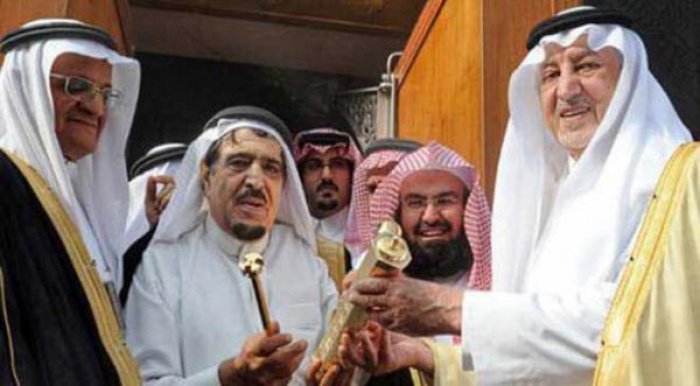 Во время установки нового замка на двери Каабы. Шейх Абдулькадир аль-Шайби получает замок из рук принца Мекки Халида аль-Файсала 